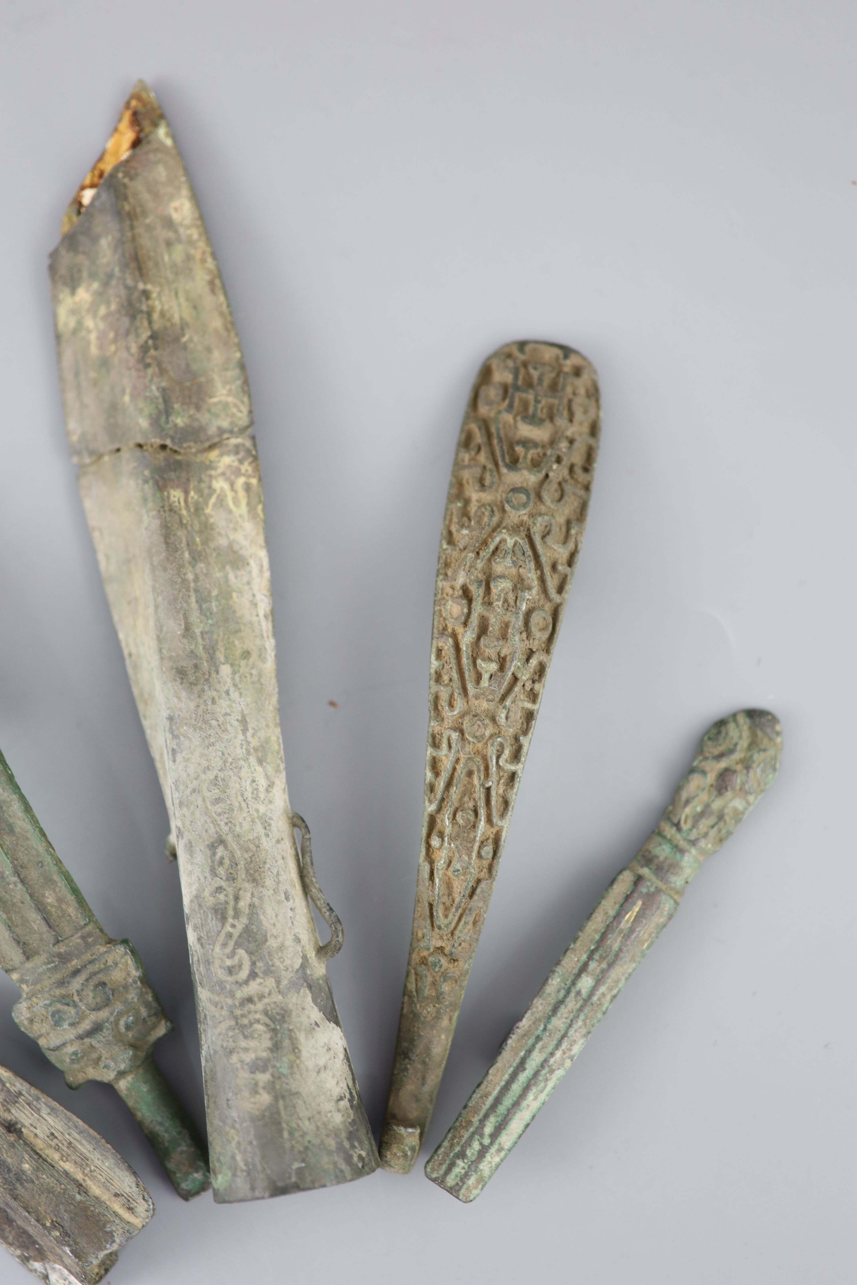 Three Chinese archaic bronze belt hooks and two spear heads, Warring States / Han dynasty